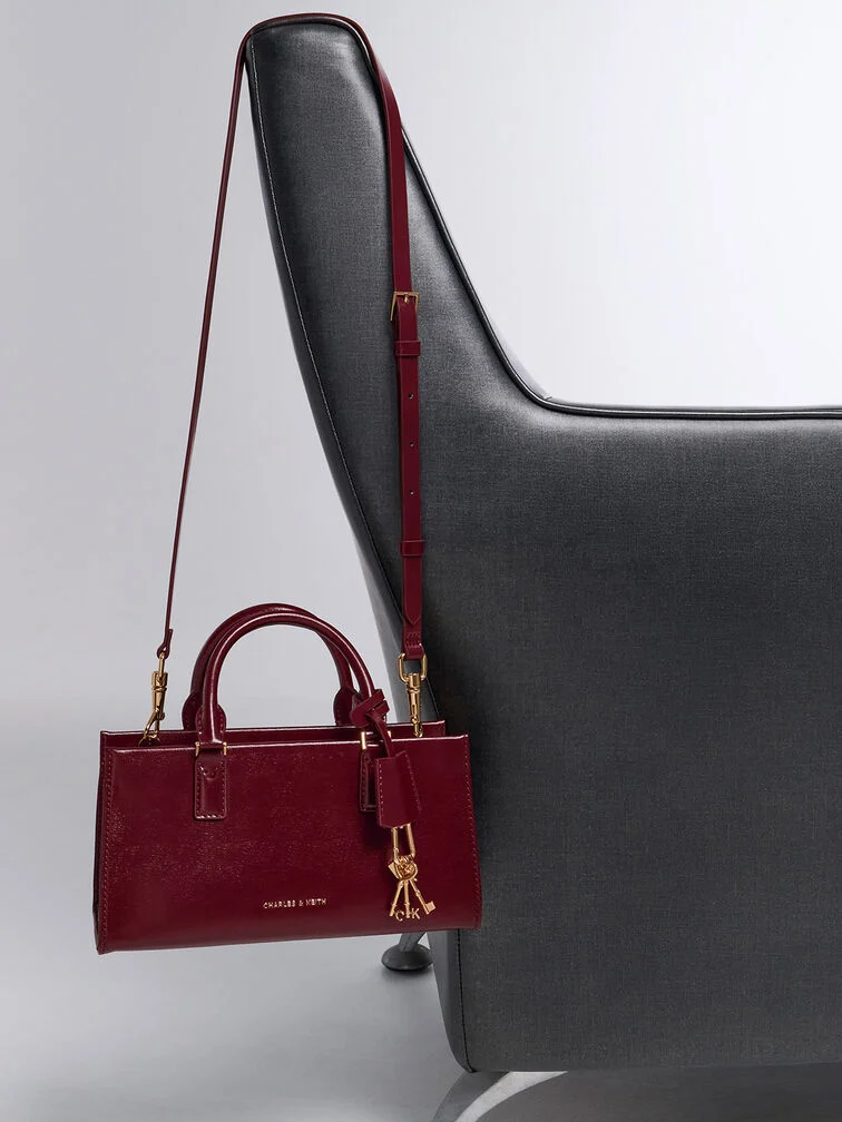 Dark red top-handle bag, chic and compact for evening outings.