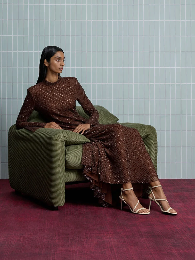 Strappy stiletto sandals paired with a dark brown sequinned maxi dress for a glamorous fall wedding guest look.